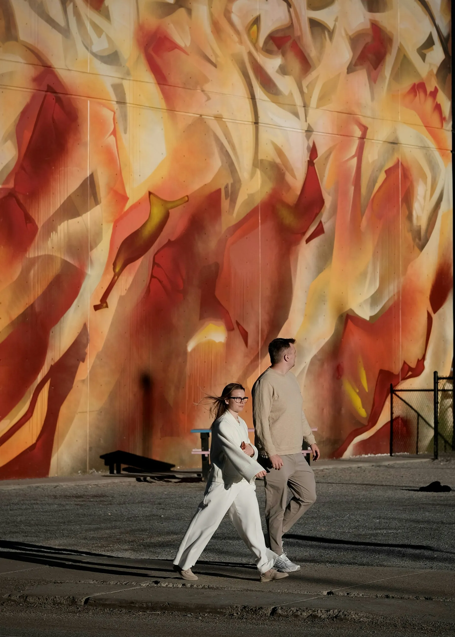 Two people walking past a vibrant abstract wall mural