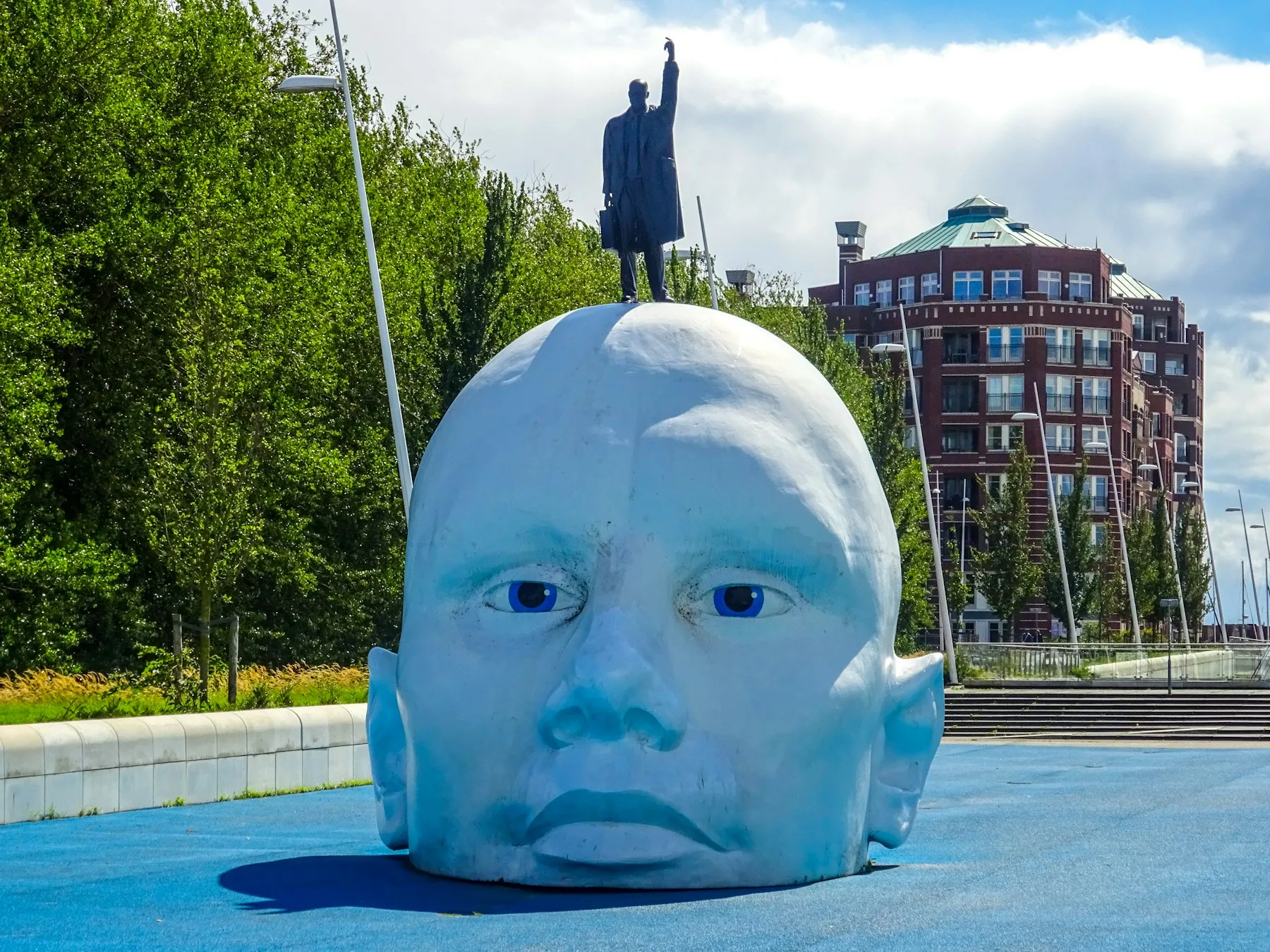 A giant blue head sculpture with a person standing on top